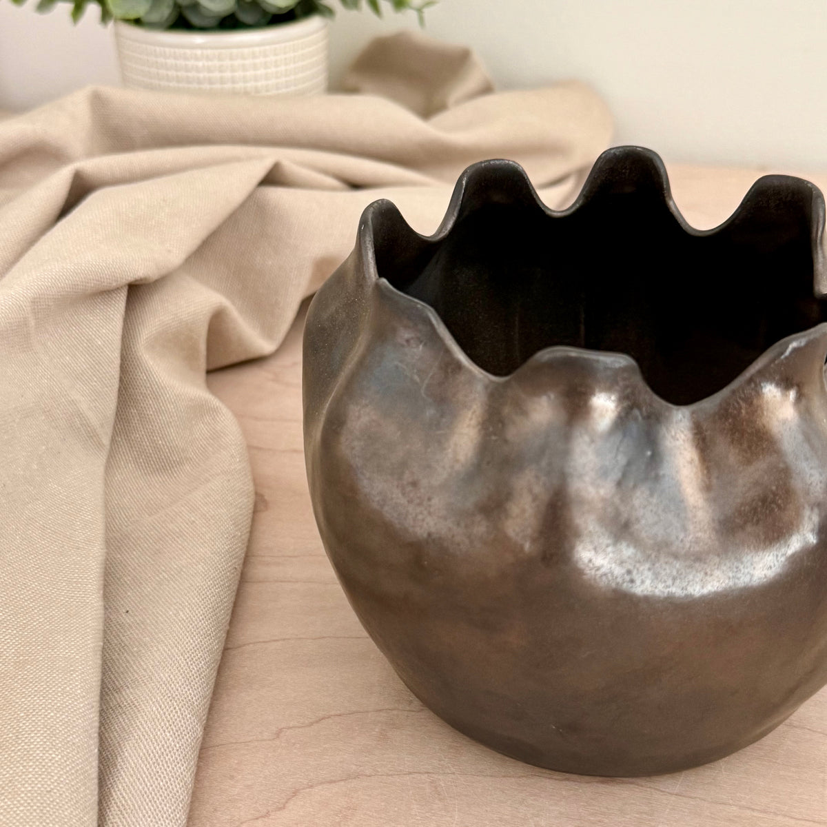 Side view of handmade stoneware ruffle rim vase showing iridescent glaze